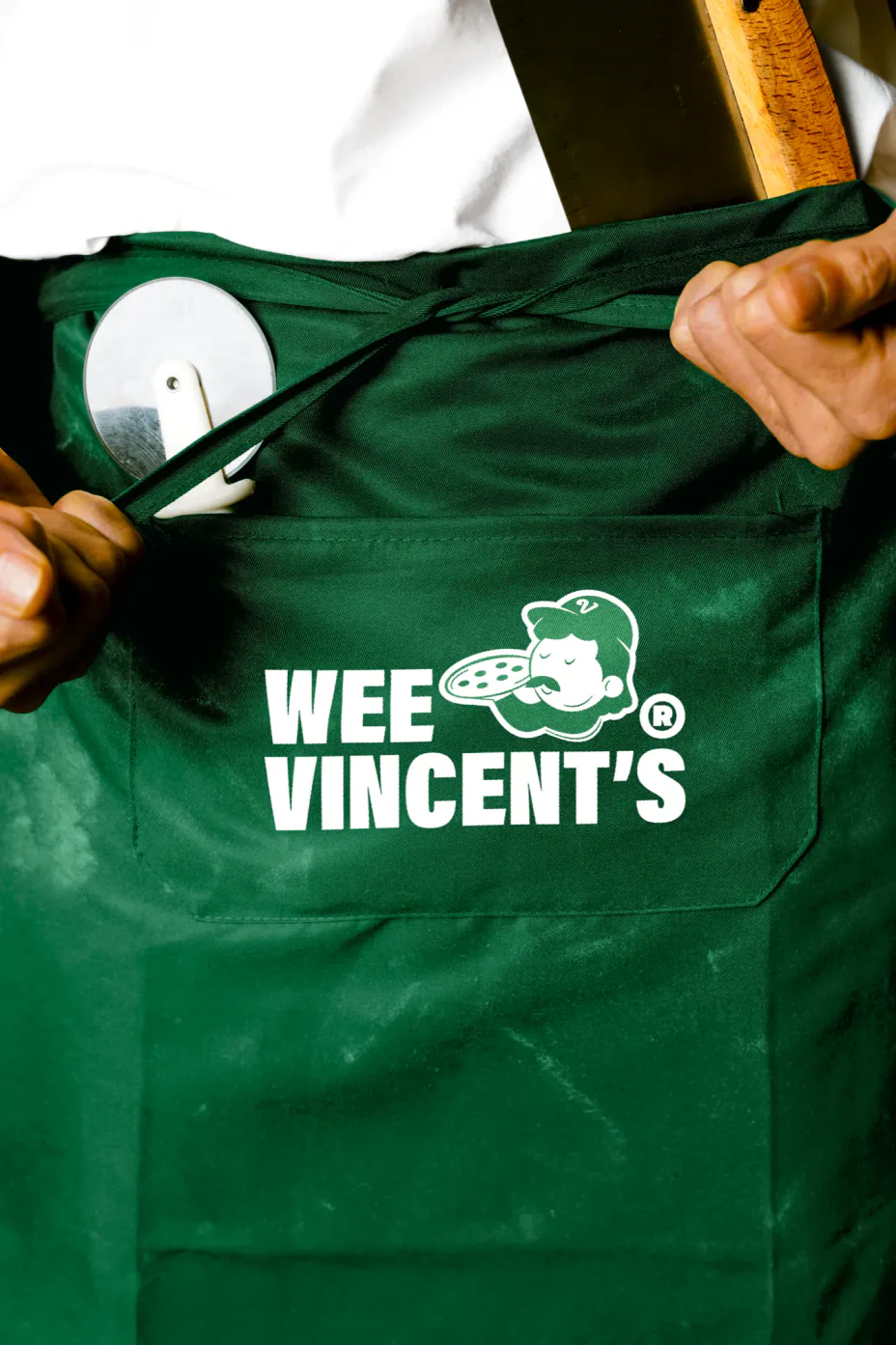 A green Wee Vincent’s apron with the mascot lockup on the pocket