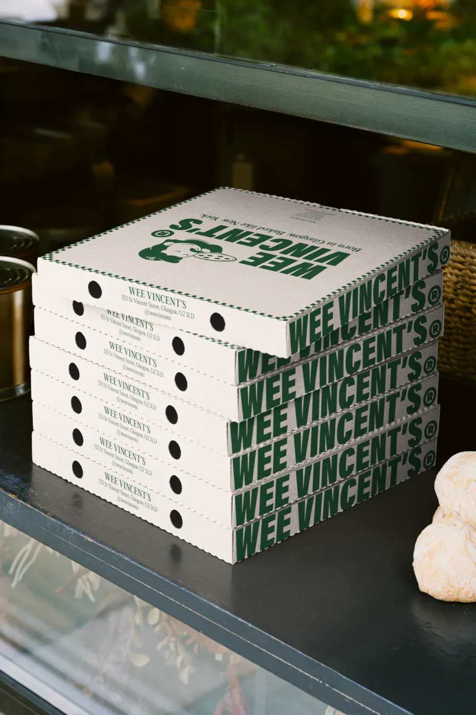 A stack of Wee Vincent’s pizza boxes carrying the address and the wordmark down the side